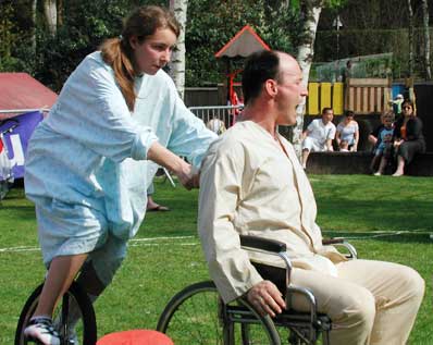 homme en chaise roulante pouss par une infirmire sur un monocycle